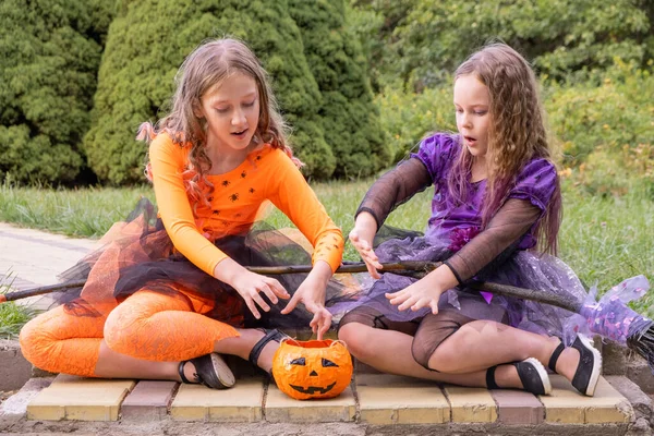 Halloween gyerek lányok jelmez boszorkányok varázsolnak egy tök. — Stock Fotó