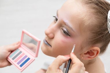 Makyaj sanatçısı güzel bir genç kız için ışıltılı bir makyaj yapıyor. Cadılar Bayramı ya da yeni yıl için makyaj.