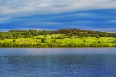 Göl ve orman ufukta ile çiçek açması çayır üzerinde gündoğumu.