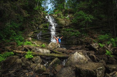 Sırt çantalı gezgin şelale manzarasının keyfini çıkarıyor. Seyahat ve özgürlük.