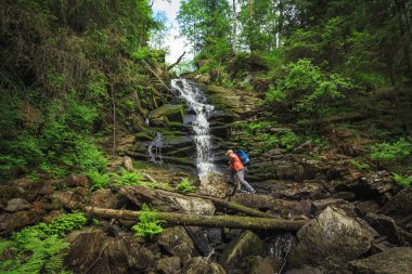 Sırt çantalı bir gezgin nehri şelaleyle geçer. Seyahat ve özgürlük.