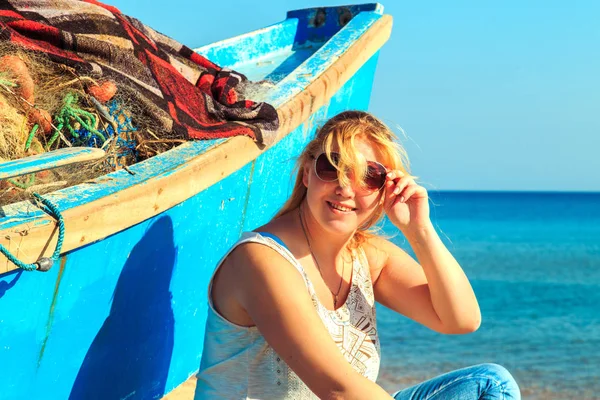 Kumsalda yaşlı balıkçı teknesinin yanında çekici yalnız bir kız..