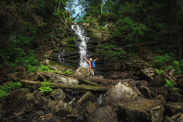 Sırt çantalı gezgin şelale manzarasının keyfini çıkarıyor. Seyahat ve özgürlük.