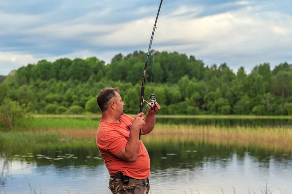 成熟した男は明け方湖畔に魚釣り — ストック写真