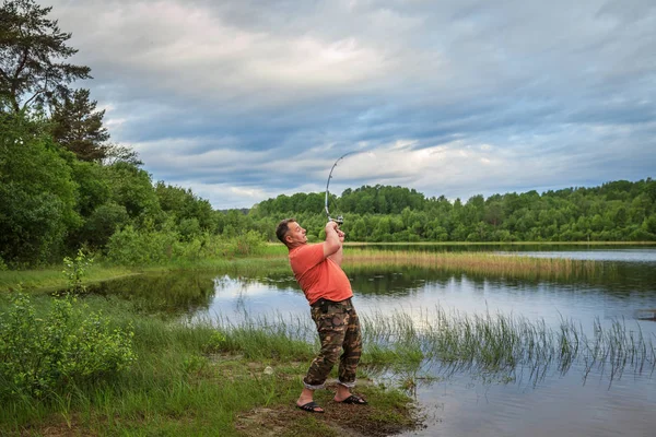 成熟した男は明け方湖畔に魚釣り — ストック写真