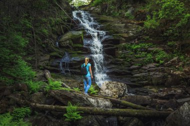 Kız gezgin bir orman şelale yakınında. Gevşeme ve özgürlük hissi.