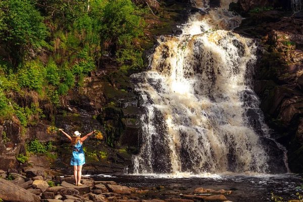 Buket çiçek yakınındaki bir orman şelale ile şapkalı kadın. Gevşeme ve özgürlük hissi.