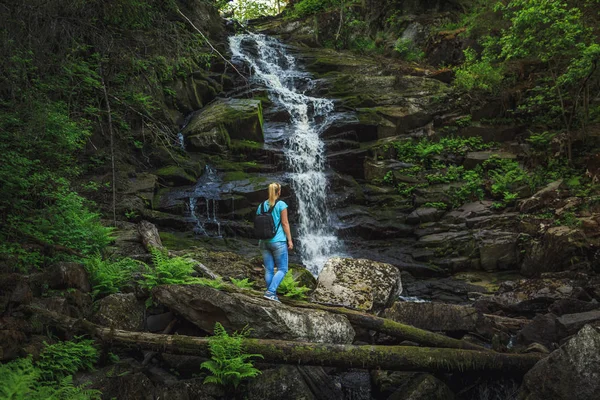 Kız gezgin bir orman şelale yakınında. Gevşeme ve özgürlük hissi.