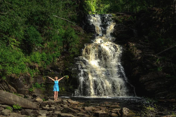 Buket çiçek yakınındaki bir orman şelale ile şapkalı kadın. Gevşeme ve özgürlük hissi.