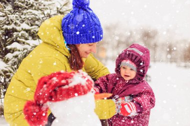 Anne ve bebek kış parkta oynuyorlar. Kış eğlence.