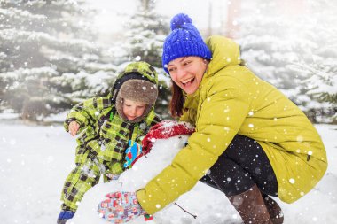 Anne ve bebek kış parkta oynuyorlar. Kış eğlence.