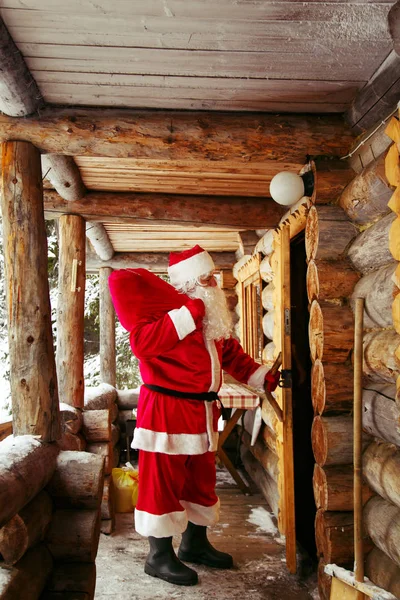 The real Santa Claus knocks on the door of the hut in the winter forest.