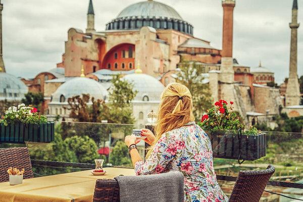 Girl drinks Turkish coffee enjoying the view of the Hagia Sophia Museum. Istanbul, Turkey.