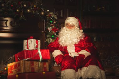 Otantik Noel Baba Noel ağacı yakınındaki oturma odasında oturuyor. Atmosfer kutlama ve büyü.