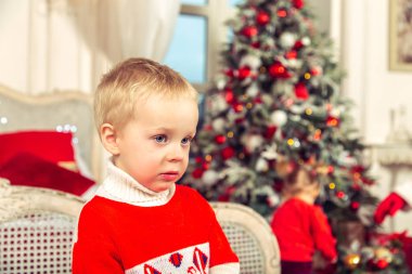 Küçük üzgün çocuk Noel ağacı arka plan üzerinde şenlikli bir yatak odasında.
