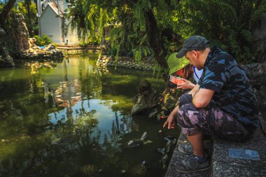 Turistler Wat Prayoon tapınağındaki kaplumbağaları besler. Bangkok, Tayland.