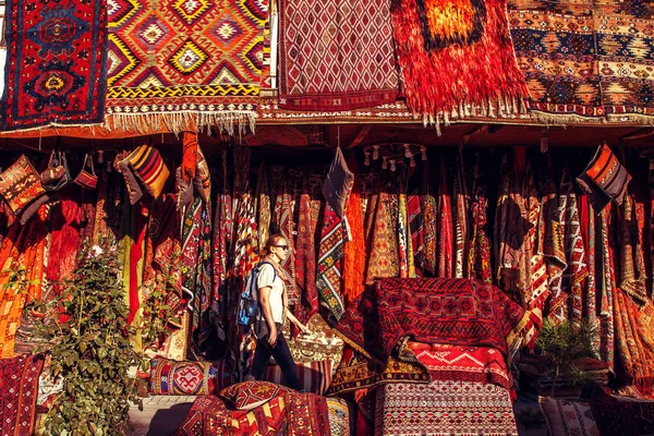 Girl tourist on background turkish carpets in souvenir shop. Cappadocia, Turkey.