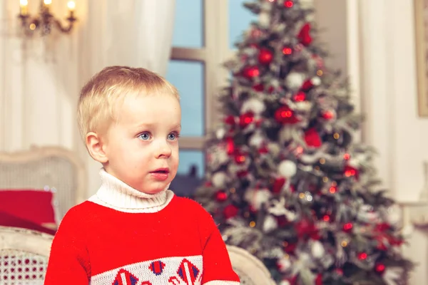 圣诞树背景上节日卧室里的悲伤小男孩 — 图库照片