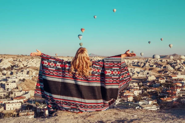 Girl at dawn watching the balloons and enjoying life. Cappadocia, Goreme, Turkey - September 24, 2018.