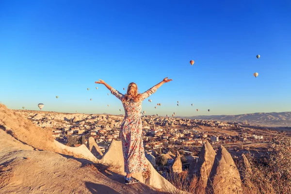 Girl at dawn watching the balloons and enjoying life. Cappadocia, Goreme, Turkey - September 24, 2018.