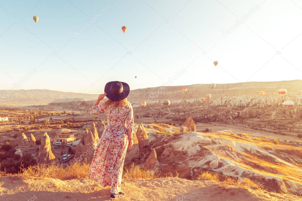 Girl at dawn watching the balloons and enjoying life. Cappadocia, Goreme, Turkey - September 24, 2018.