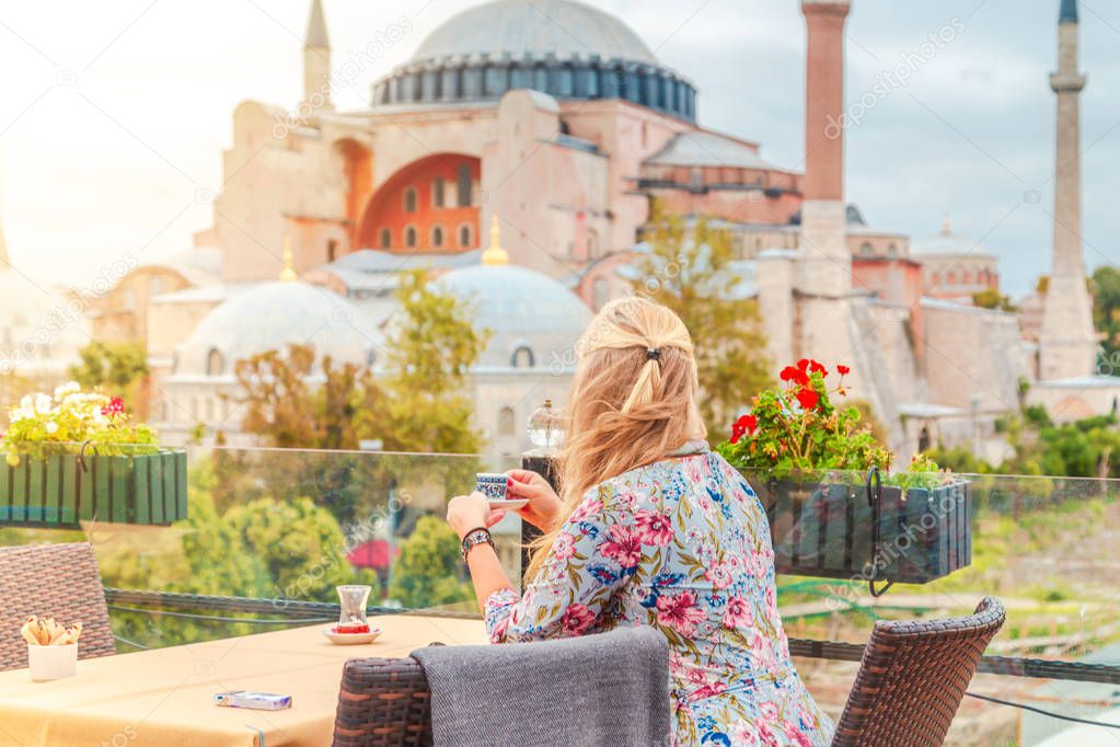 Girl drinks Turkish coffee enjoying the view of the Hagia Sophia