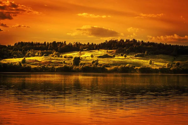 Západ slunce nad jezerem a kvetoucí loukou. — Stock fotografie