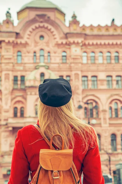 Donna con un cappotto rosso e un berretto nero guarda una bella troia rosa — Foto Stock