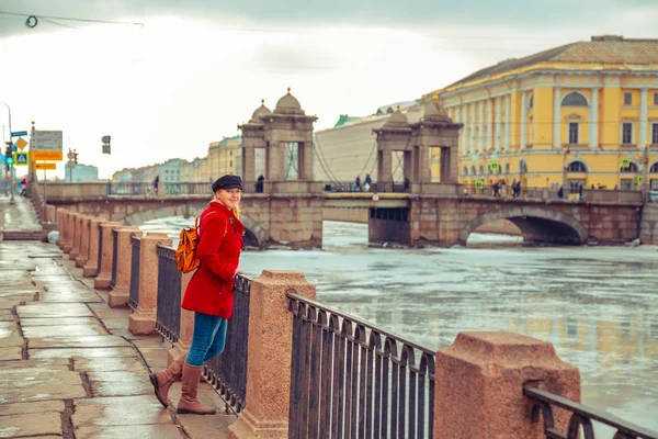 Ξανθιά σε ένα κόκκινο παλτό περπατά κατά μήκος το ανάχωμα του Φοντάνκα το — Φωτογραφία Αρχείου