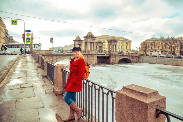 赤いコートを着た金髪、フォンタンカの堤防に沿って歩く — ストック写真