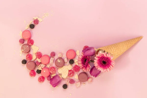 Mix of flowers and sweets in a waffle cone.