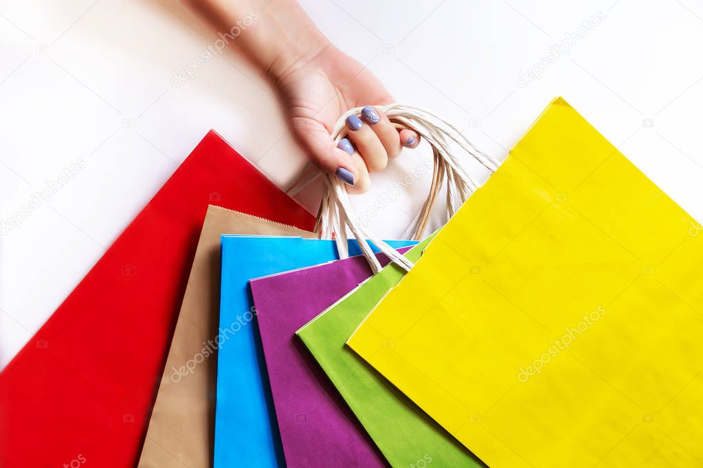 Hand holding colorful paper bags on a white background. 