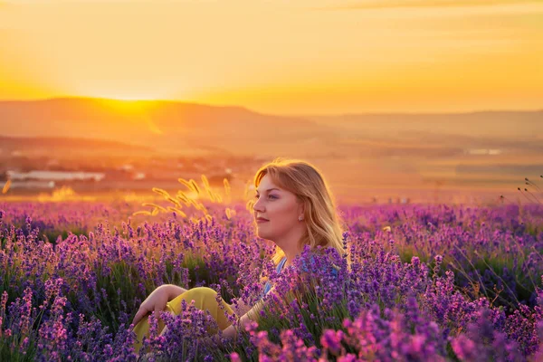 Uma rapariga num campo de lavanda ao pôr-do-sol. Noite de verão ensolarado em Crim — Fotografia de Stock