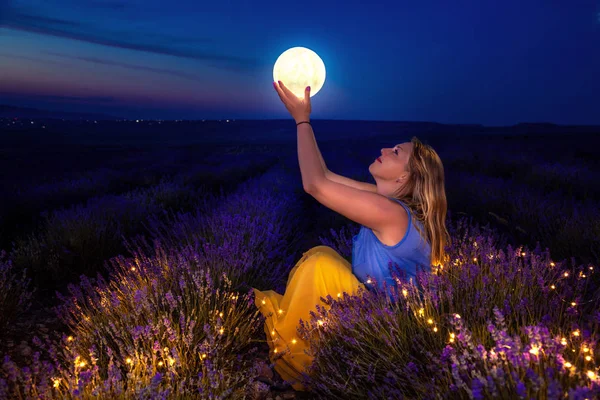 その少女は月を手に持っている。夜のラベンダー畑. — ストック写真