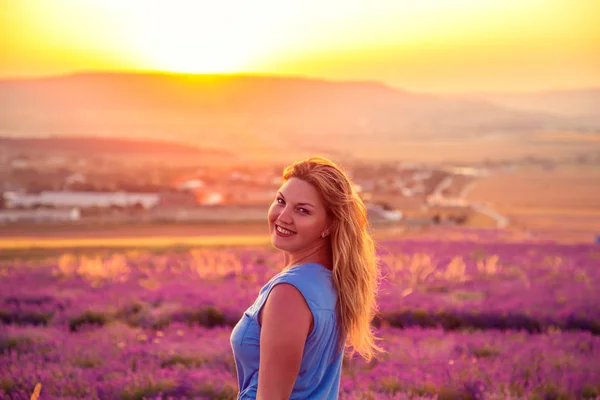 Uma rapariga num campo de lavanda ao pôr-do-sol. Noite de verão ensolarado em Crim — Fotografia de Stock