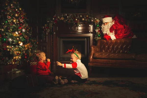 Děti si hrají poblíž vánočního stromku. Skutečný Santa Claus je w — Stock fotografie