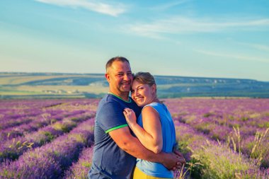 Loving couple in a lavender field at sunset. Sunny summer evenin clipart