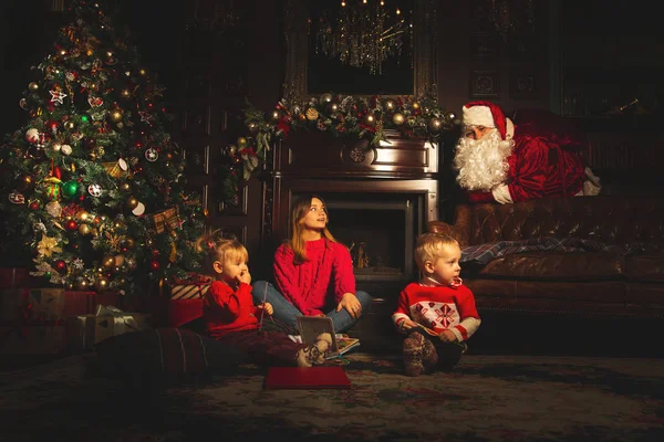 Kinder spielen in der Nähe des Weihnachtsbaums. der wirkliche Weihnachtsmann ist w — Stockfoto