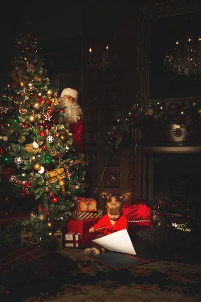 Los niños juegan cerca del árbol de Navidad. El verdadero Santa Claus es w — Foto de Stock