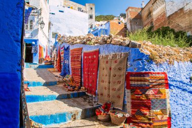 Mavi Chefchaouen sokakta geleneksel halılar. 