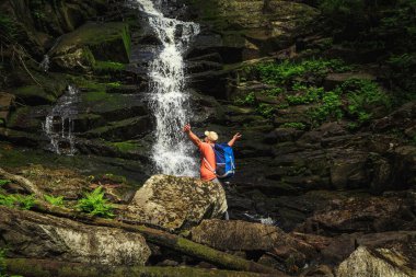 Sırt çantalı gezgin şelale manzarasının keyfini çıkarıyor. Seyahat ve özgürlük.
