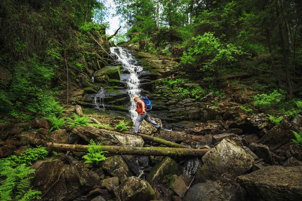 旅行者はバックパックを持って滝で川を渡ります 旅と自由 — ストック写真