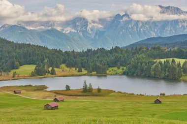 Dağ kulübeleri ve Alplerinde dağ gölü olan güzel bir dağ manzarası..