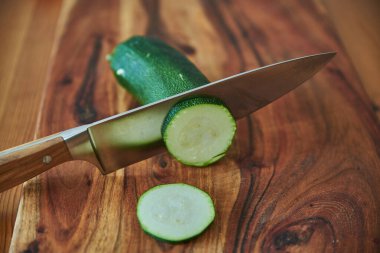 Ahşap bir kesme tahtasının üzerinde şefin bıçağı ve sebzeleri. Bıçak ve sebzelerle tahta doğrama tahtası..