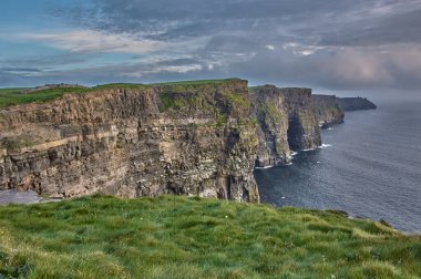 İrlanda 'nın Moher Kayalıkları' nın panoramik manzarası. Günbatımında Moher Kayalıkları. İrlanda 'nın kıyı şeridinde büyük uçurumlar var. Anne kayalıklarında gün batımı.