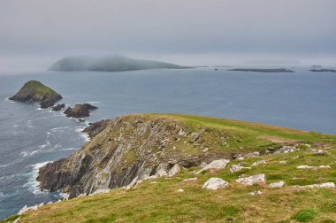 İrlanda 'daki Dingle Yarımadası' ndan manzara. İrlanda kıyı şeridinde yağmur bulutları. Kocaman kayalıkları olan dalgalı İrlanda kıyıları. Dingle Yarımadası, İrlanda 'da Star Wars film mekanı.