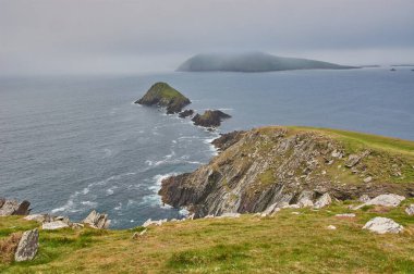 İrlanda 'daki Dingle Yarımadası' ndan manzara. İrlanda kıyı şeridinde yağmur bulutları. Kocaman kayalıkları olan dalgalı İrlanda kıyıları. Dingle Yarımadası, İrlanda 'da Star Wars film mekanı.