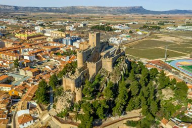 İspanya 'da kırmızı çatı evlerinin dairesel halkasıyla çevrili platodan yükselen donjon ve avlu ortaçağ Almansa kalesinin havadan görünüşü, ünlü bir savaş alanı.