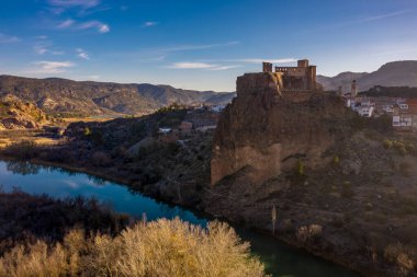 İspanya 'daki Cabriel nehrinin üzerinde kısmen restore edilmiş ortaçağ kalesinin hava panoramik manzarası yansıması ve dramatik gökyüzü ile