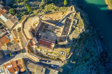 İspanya 'daki Cabriel nehrinin üzerinde kısmen restore edilmiş ortaçağ kalesinin hava panoramik manzarası yansıması ve dramatik gökyüzü ile